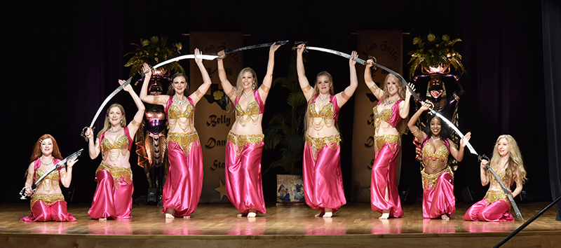 raksettes performers wearing pink and posing with swords on stage
